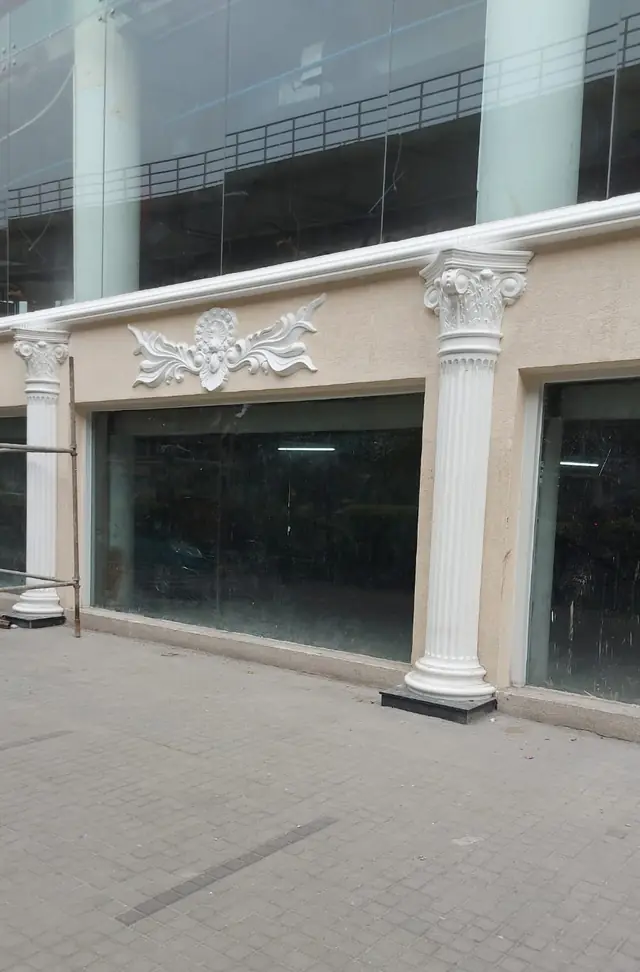 Corner of the mall with columns, a cornice and a carved panel