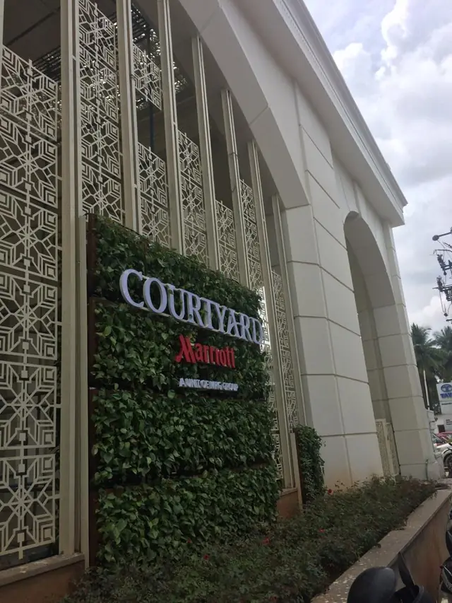 Geometric jali screens beside the Courtyard by Marriott sign and green wall