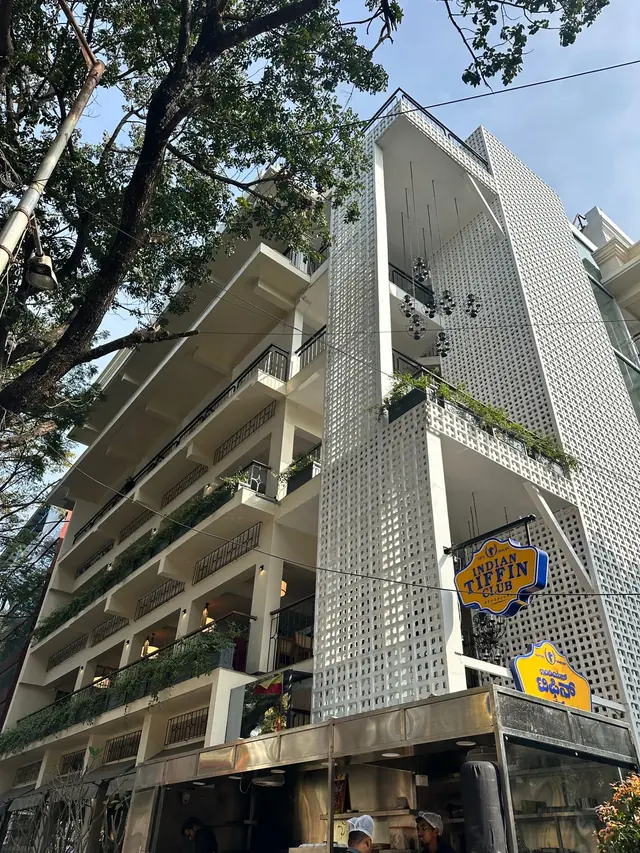 The restaurant's jali facade seen from the street through trees