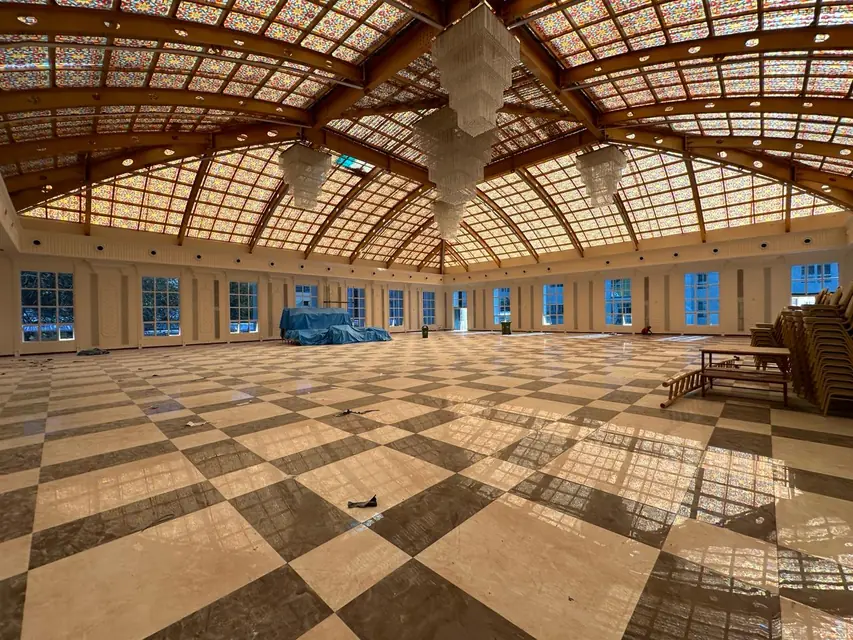 Inside the hall, with mouldings around the windows under a coloured-glass roof